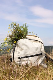 Bouquet of beautiful yellow flowers and backpack near mountains outdoors