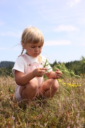 Photo of Little girl with bouquet of wildflowers at field