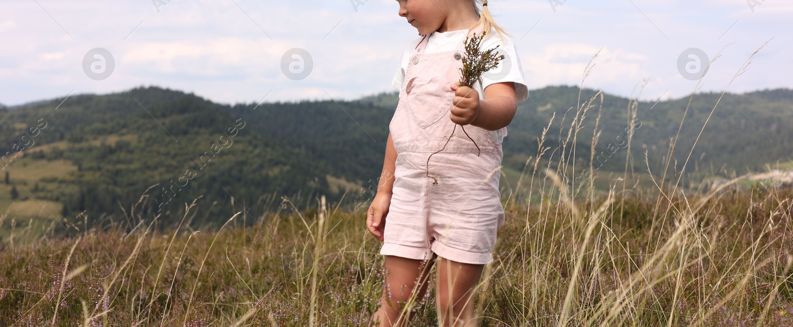 Photo of Smiling little girl with bouquet of wildflowers at field, closeup