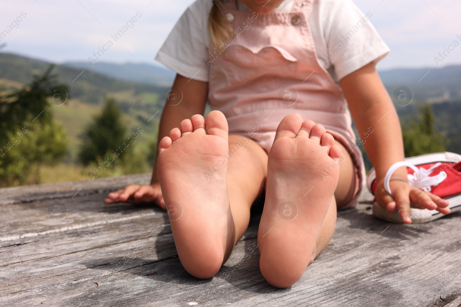 Photo of Little girl sitting on wooden deck outdoors, closeup