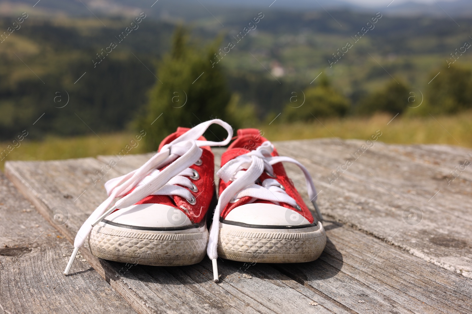 Photo of Pair of red shoes on wooden surface in mountains