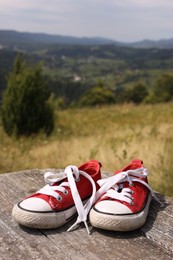 Pair of red shoes on wooden surface in mountains, space for text