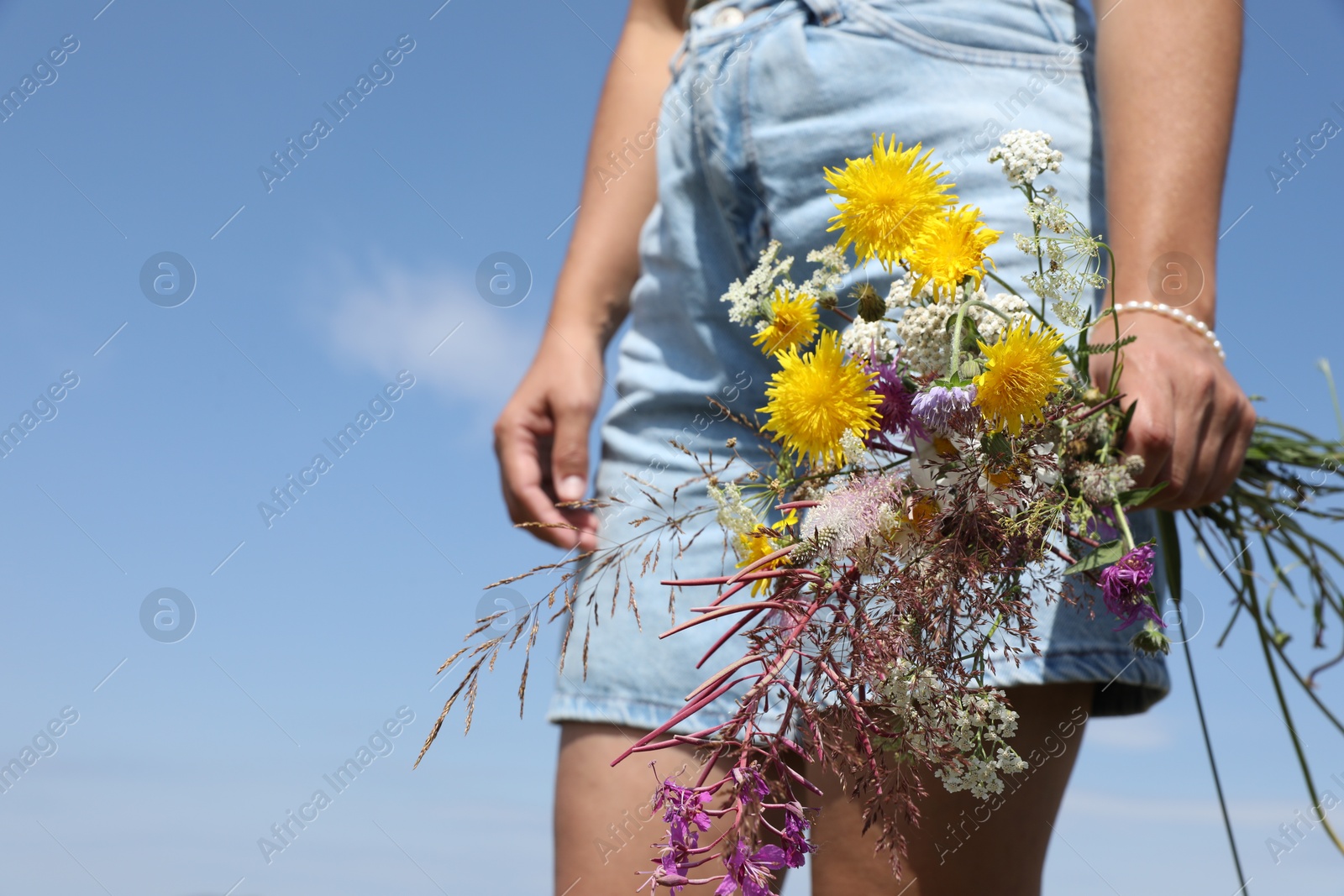 Photo of Woman holding bouquet of wild flowers outdoors, closeup