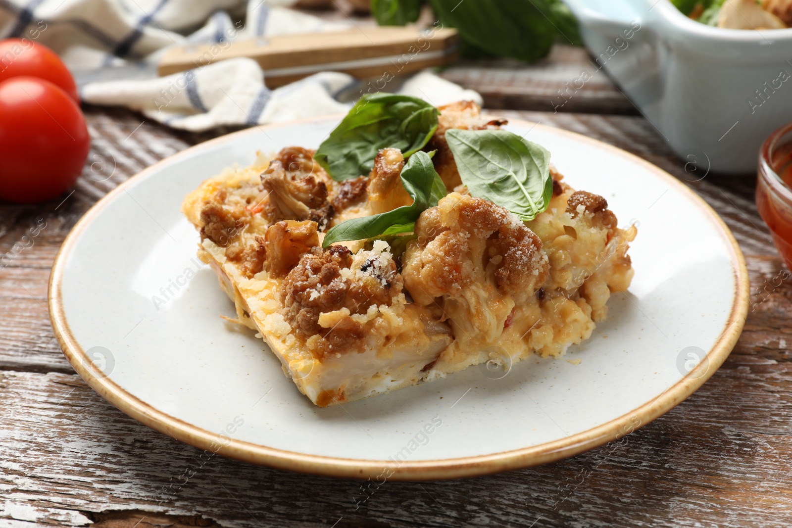 Photo of Tasty baked cauliflower and basil on wooden table, closeup