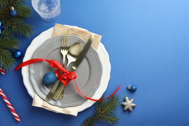 Photo of Beautiful Christmas setting with plates, elegant cutlery and festive decor on blue table, flat lay. Space for text