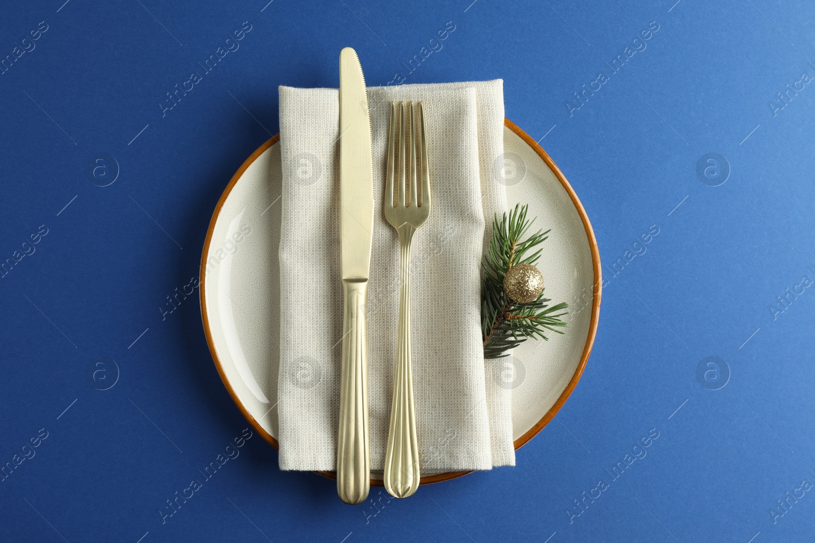 Photo of Beautiful Christmas setting with plate, elegant cutlery and festive decor on blue table, top view