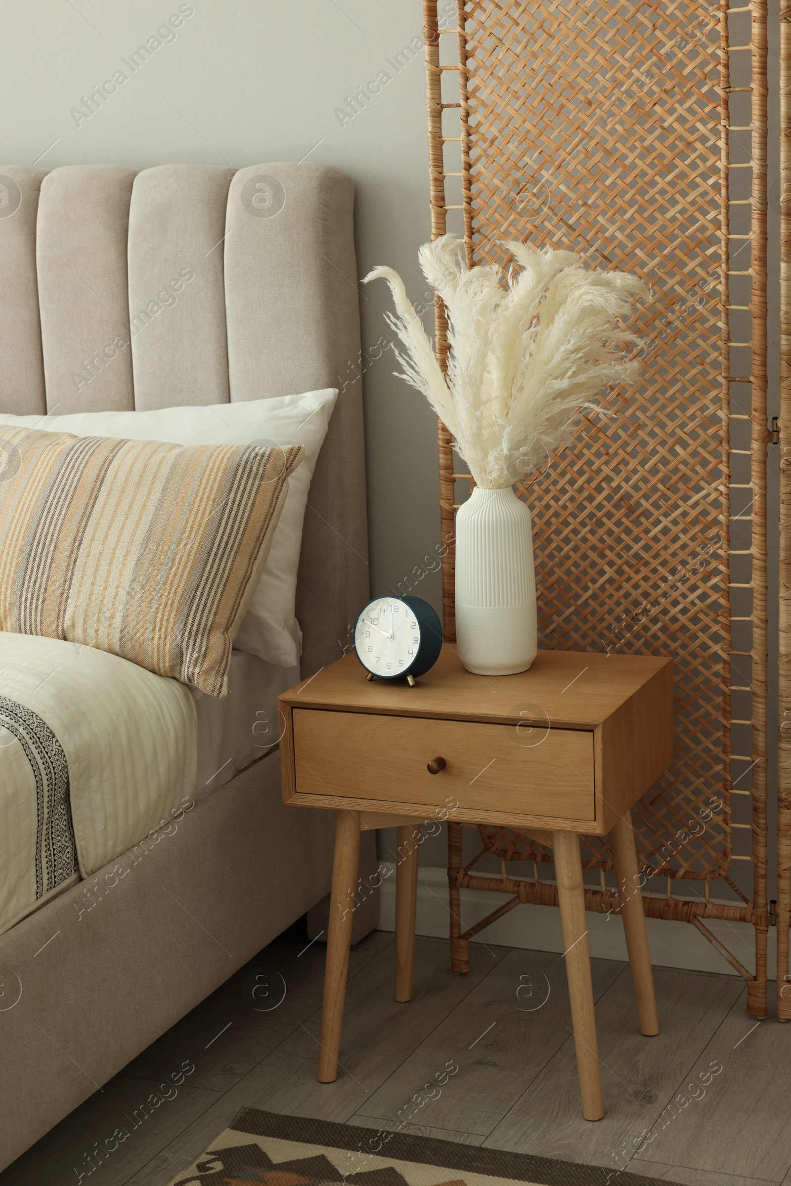 Photo of Large bed, folding screen and bedside table in stylish room