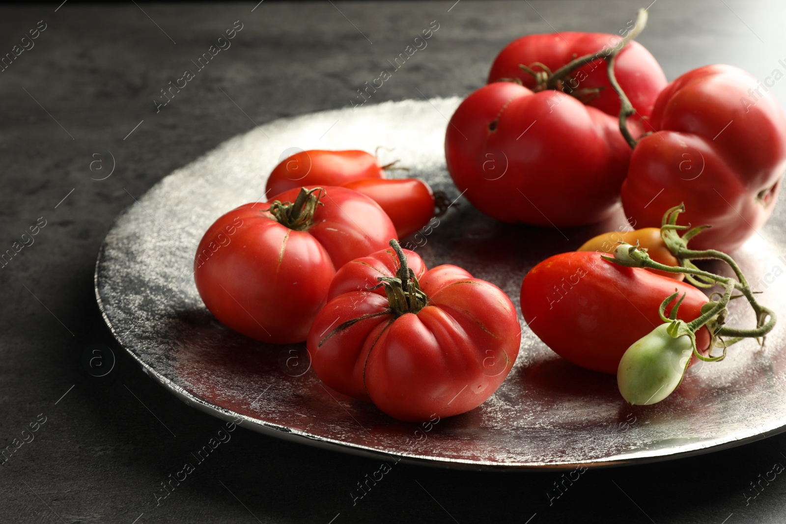 Photo of Different ripe and unripe tomatoes on grey table, closeup