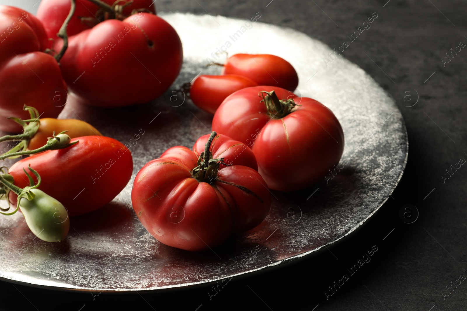 Photo of Different ripe and unripe tomatoes on grey table, closeup