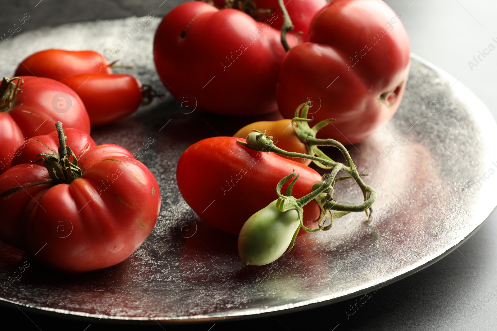 Photo of Different ripe and unripe tomatoes on grey table, closeup