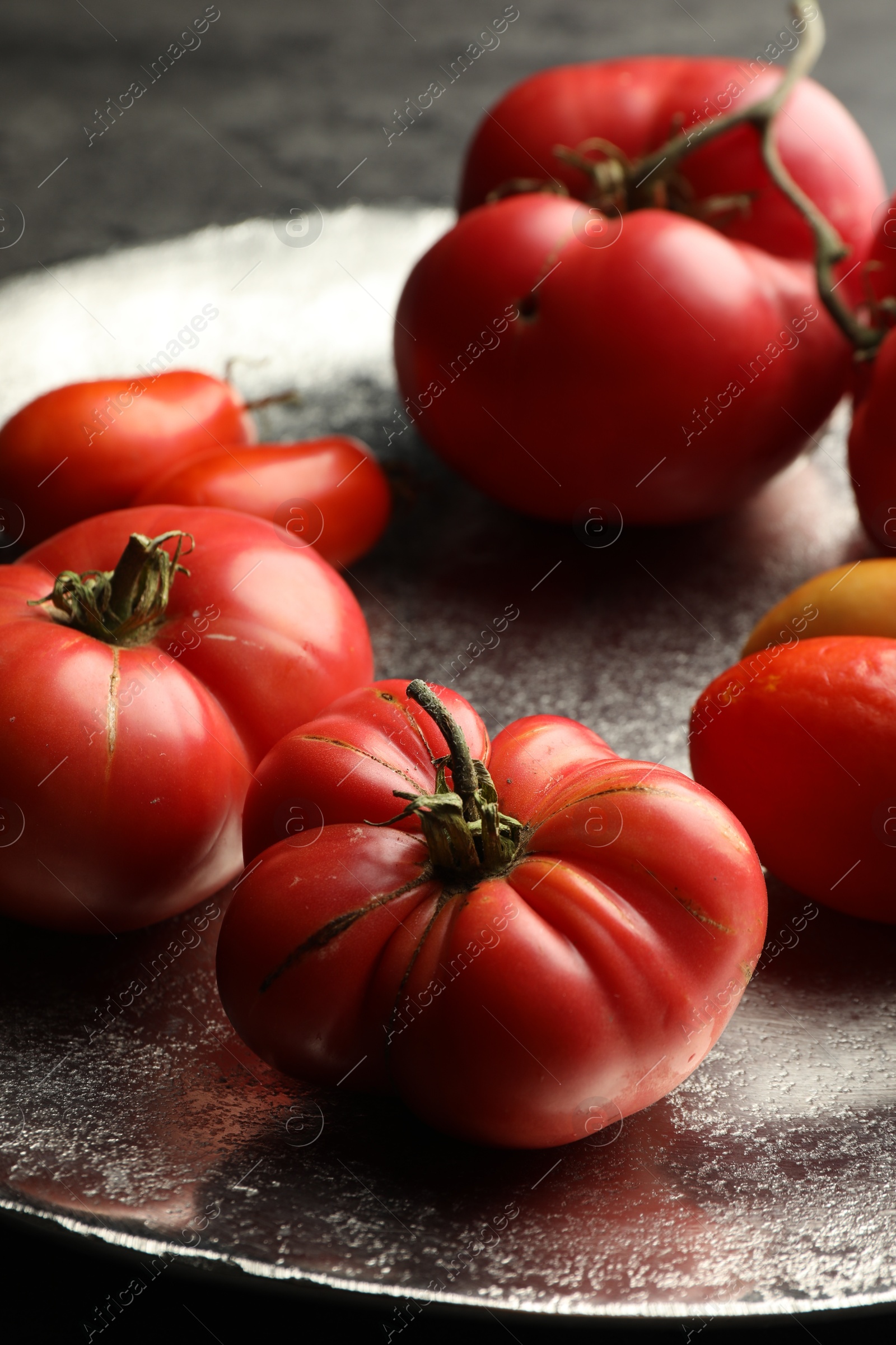 Photo of Different ripe tomatoes on grey table, closeup