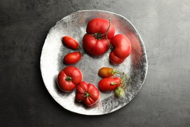 Different ripe and unripe tomatoes on grey table, top view