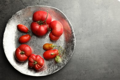 Photo of Different ripe and unripe tomatoes on grey table, top view. Space for text