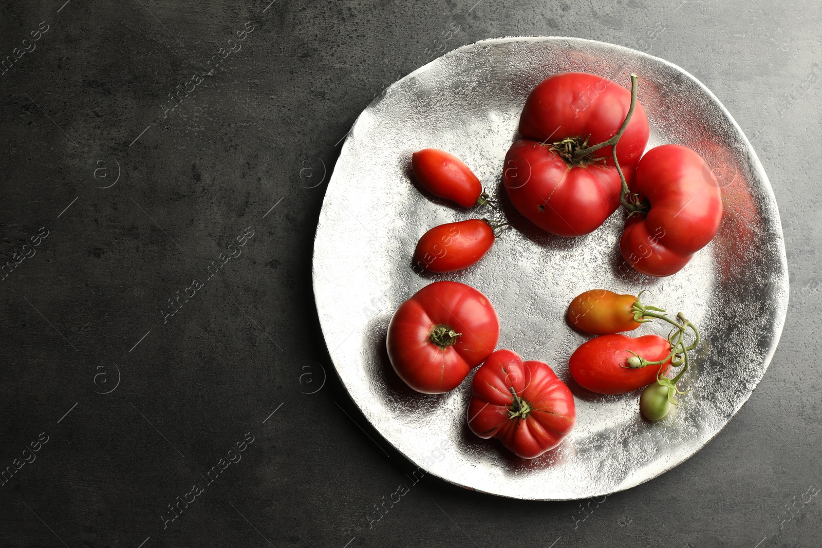 Photo of Different ripe and unripe tomatoes on grey table, top view. Space for text