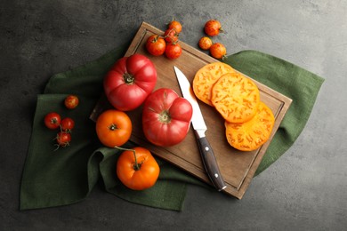 Photo of Whole and cut ripe tomatoes with knife on grey table, flat lay