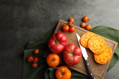 Whole and cut ripe tomatoes with knife on grey table, flat lay. Space for text