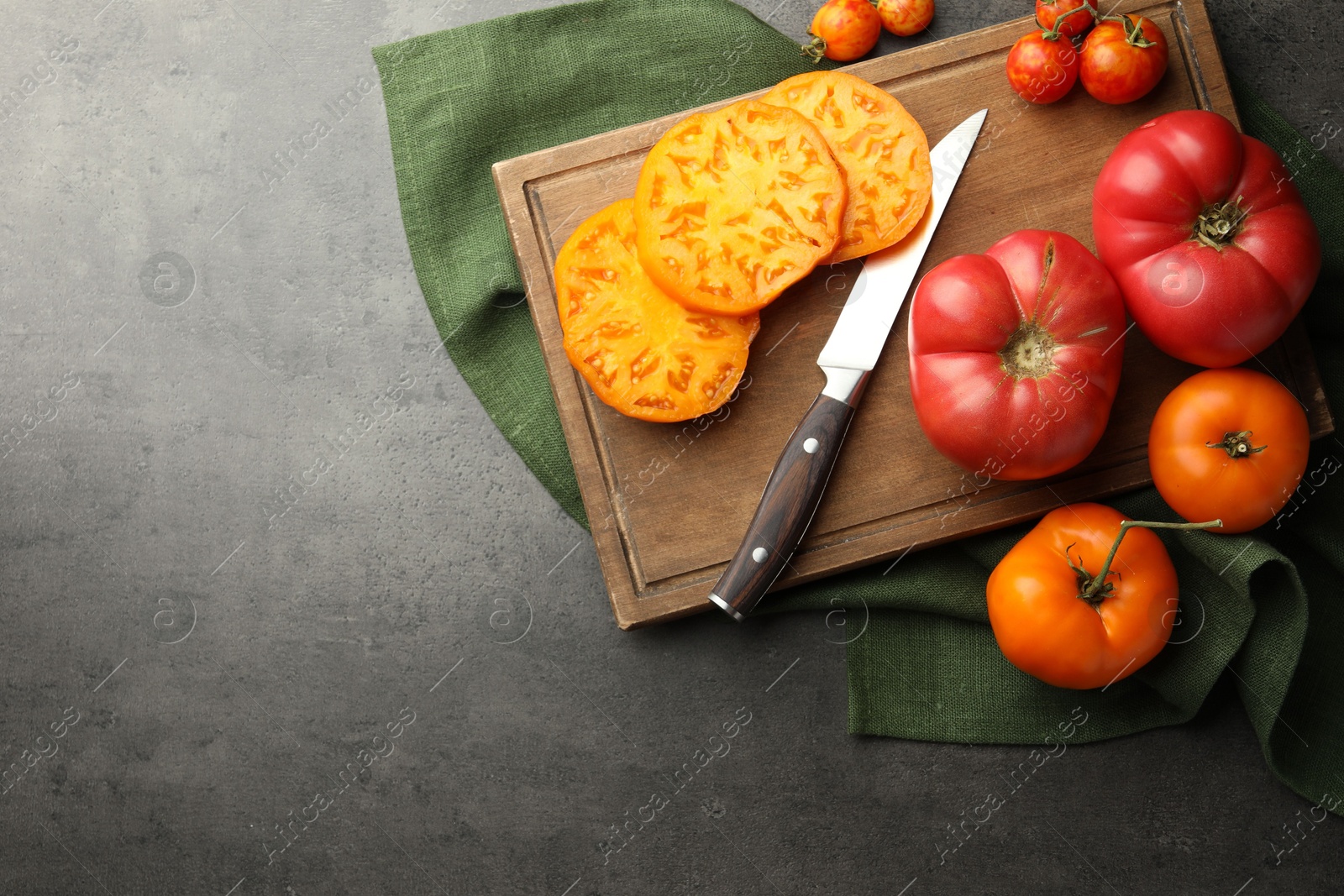 Photo of Whole and cut ripe tomatoes with knife on grey table, flat lay. Space for text