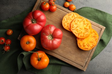 Photo of Whole and cut ripe tomatoes on grey table, flat lay