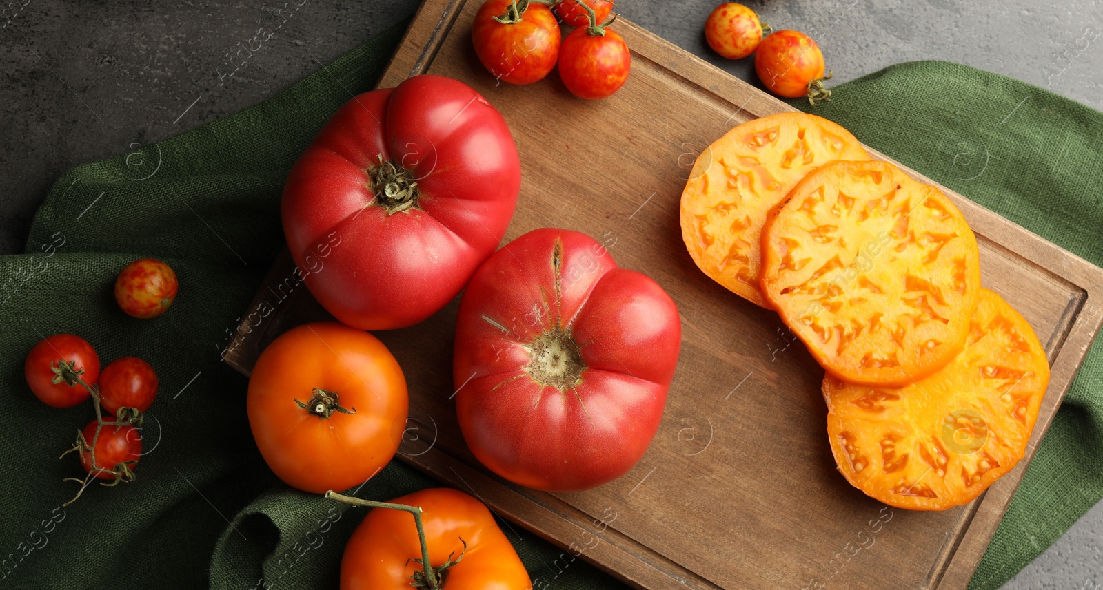 Photo of Whole and cut ripe tomatoes on grey table, flat lay