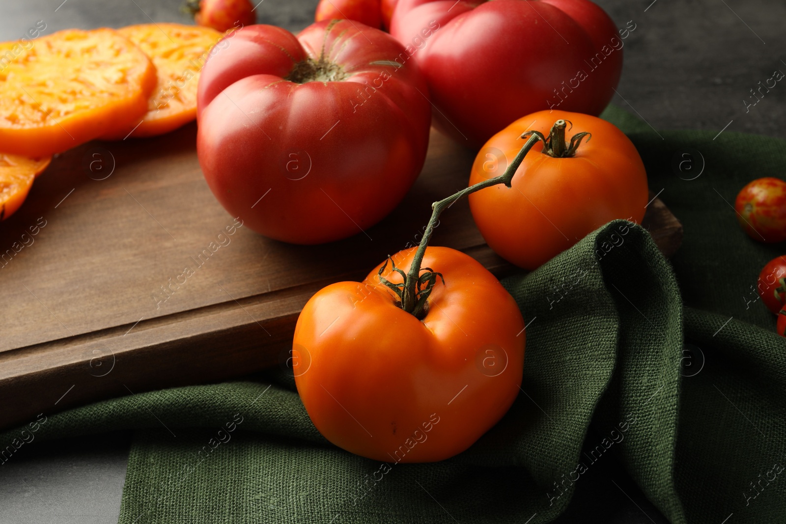 Photo of Different ripe tomatoes on grey table, closeup