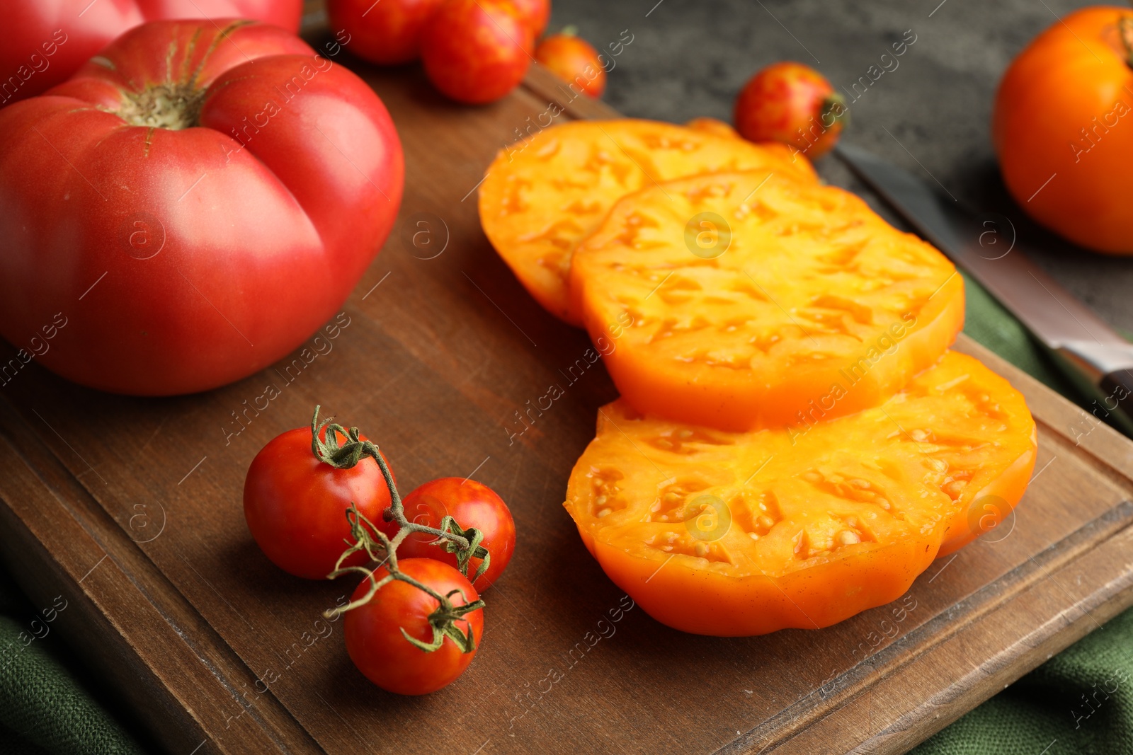 Photo of Cut and whole ripe tomatoes on grey table, closeup