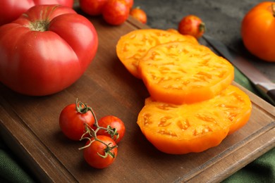 Cut and whole ripe tomatoes on grey table, closeup