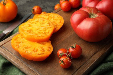 Cut and whole ripe tomatoes on grey table, closeup