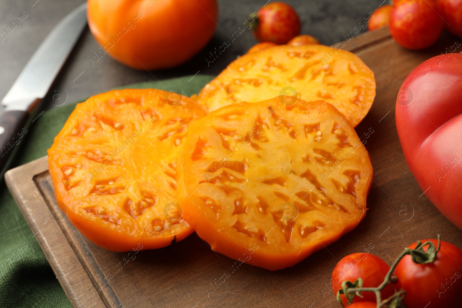 Photo of Cut and whole ripe tomatoes on grey table, closeup