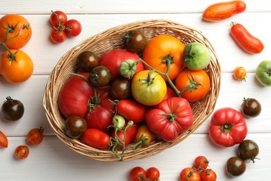 Different ripe and unripe tomatoes on white wooden table, flat lay