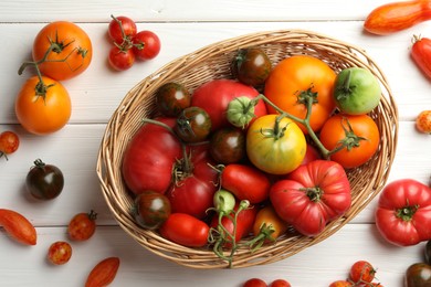 Photo of Different ripe and unripe tomatoes on white wooden table, flat lay