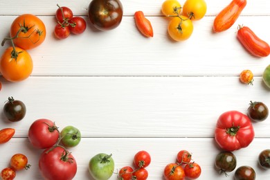 Frame made of different ripe and unripe tomatoes on white wooden table, flat lay. Space for text