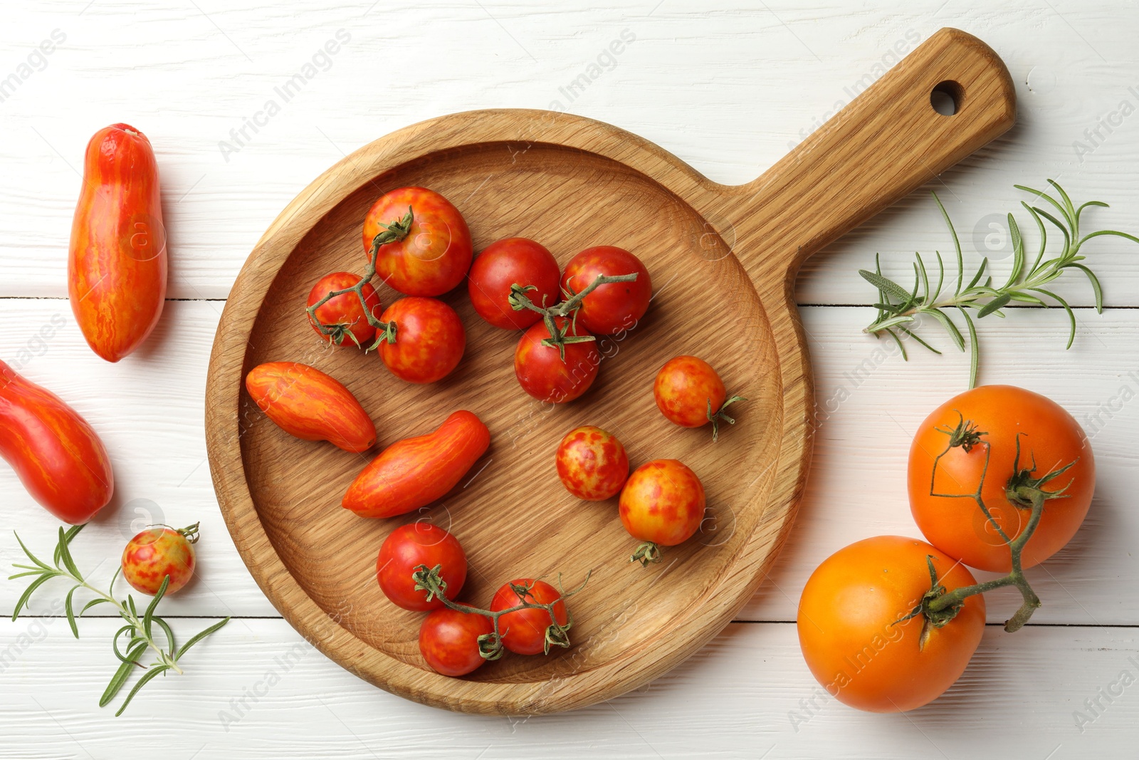 Photo of Different ripe tomatoes and rosemary on white wooden table, flat lay