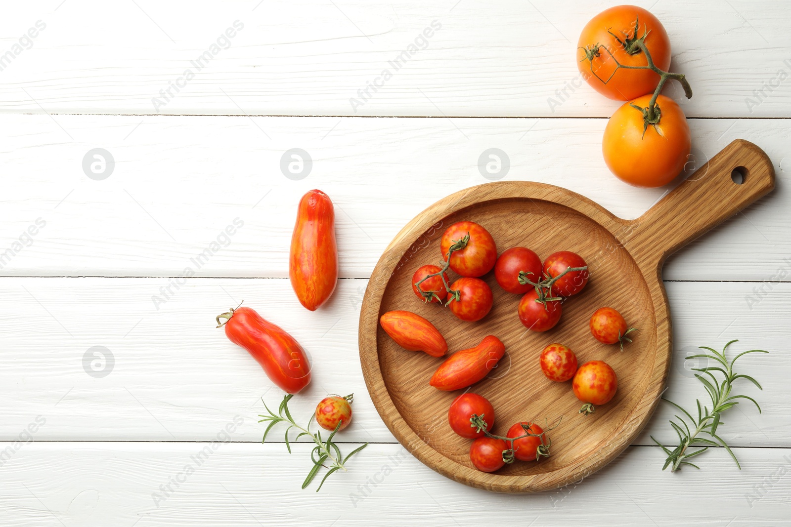 Photo of Different ripe tomatoes and rosemary on white wooden table, flat lay. Space for text