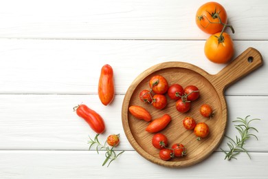 Different ripe tomatoes and rosemary on white wooden table, flat lay. Space for text