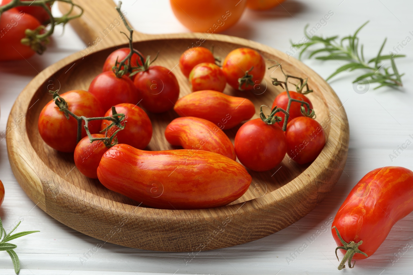 Photo of Different ripe tomatoes on white wooden table, closeup