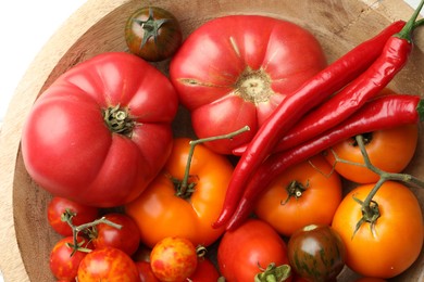 Photo of Different ripe tomatoes and chili peppers in bowl on white table, flat lay