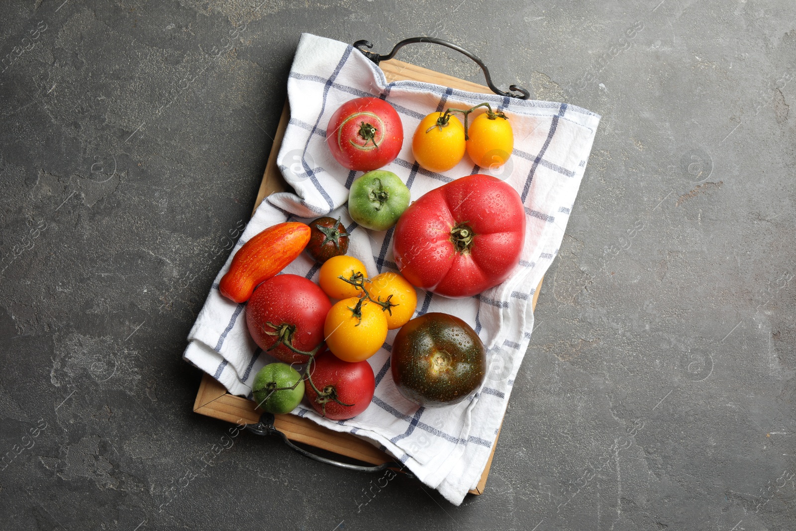 Photo of Different ripe and unripe tomatoes on grey textured table, flat lay