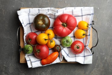 Different ripe and unripe tomatoes on grey textured table, flat lay