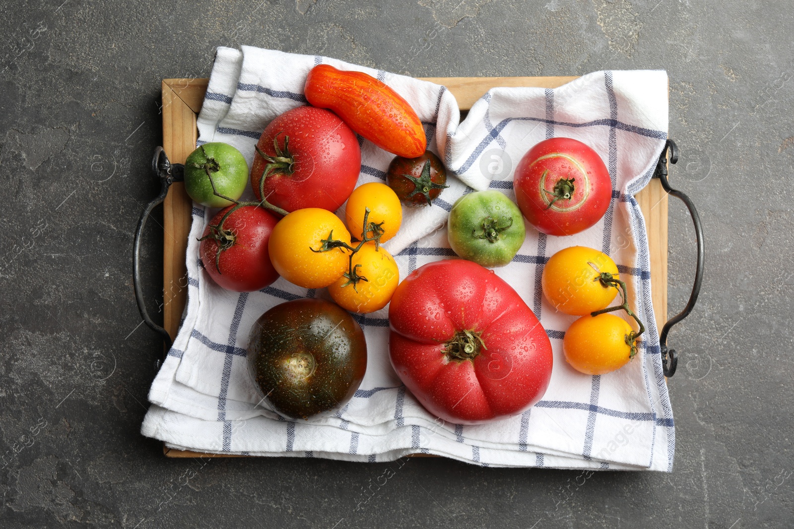 Photo of Different ripe and unripe tomatoes on grey textured table, flat lay