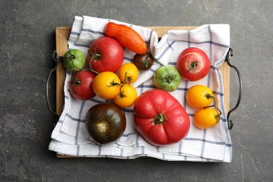 Different ripe and unripe tomatoes on grey textured table, flat lay