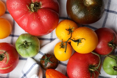 Different ripe and unripe tomatoes on tablecloth, flat lay