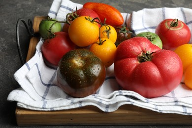 Photo of Different ripe and unripe tomatoes on grey table, closeup