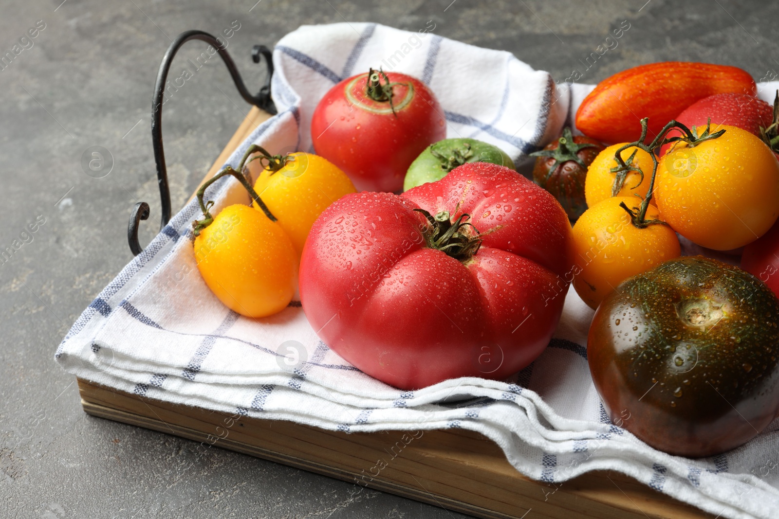 Photo of Different ripe and unripe tomatoes on grey table, closeup