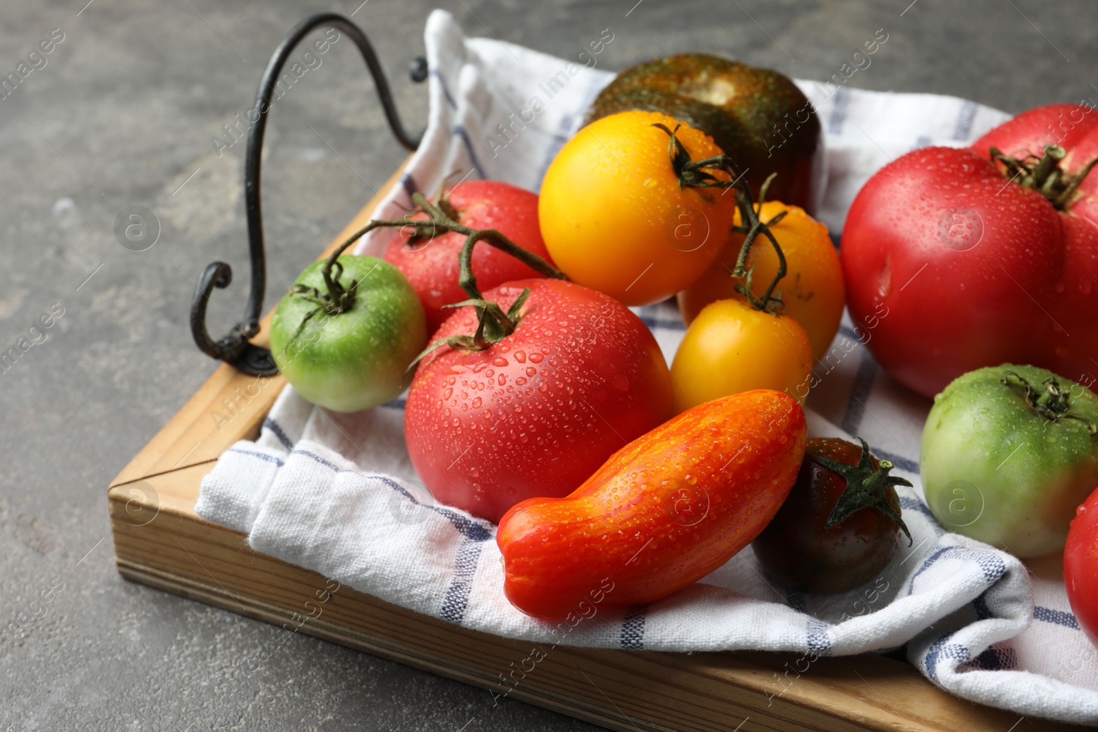 Photo of Different ripe and unripe tomatoes on grey table, closeup