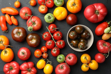 Photo of Different fresh tomatoes on grey textured table, flat lay