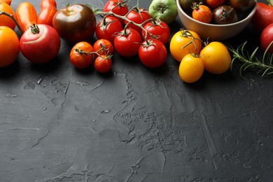 Photo of Different fresh tomatoes on grey textured table. Space for text