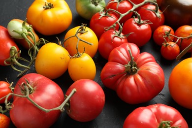 Photo of Different fresh tomatoes on grey textured table