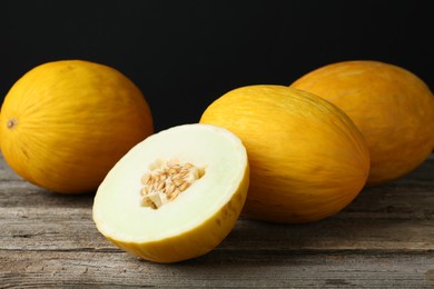 Fresh ripe melons on wooden table against black background