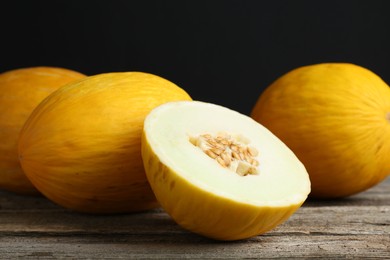 Fresh ripe melons on wooden table against black background