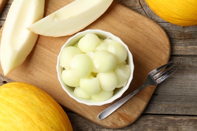 Melon balls in bowl and fresh fruits on wooden table, flat lay